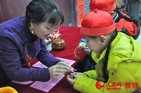 老師教小男孩編中國(guó)結(jié)。郭凱奇/攝。