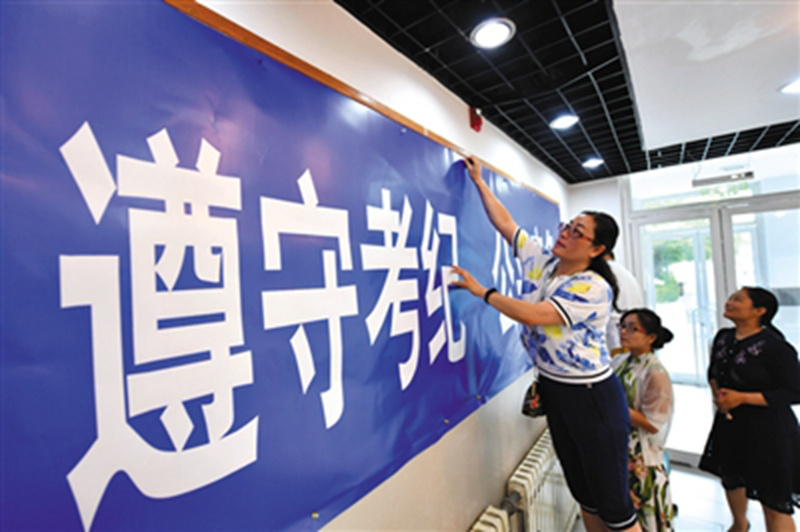 監(jiān)考老師在考場(chǎng)張貼考場(chǎng)紀(jì)律等標(biāo)語(yǔ)。李木易/攝