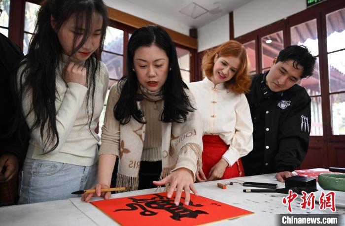 1月20日，西泠印社社員李硯（左二）為外籍留學(xué)生講述蛇年福字貼創(chuàng)作靈感。當(dāng)日，來(lái)自巴西、馬來(lái)西亞、加納、哈薩克斯坦的外籍留學(xué)生在浙江杭州西泠印社體驗(yàn)福貼、春聯(lián)和篆刻，感受古老的中國(guó)傳統(tǒng)文化。中新社記者 王剛 攝