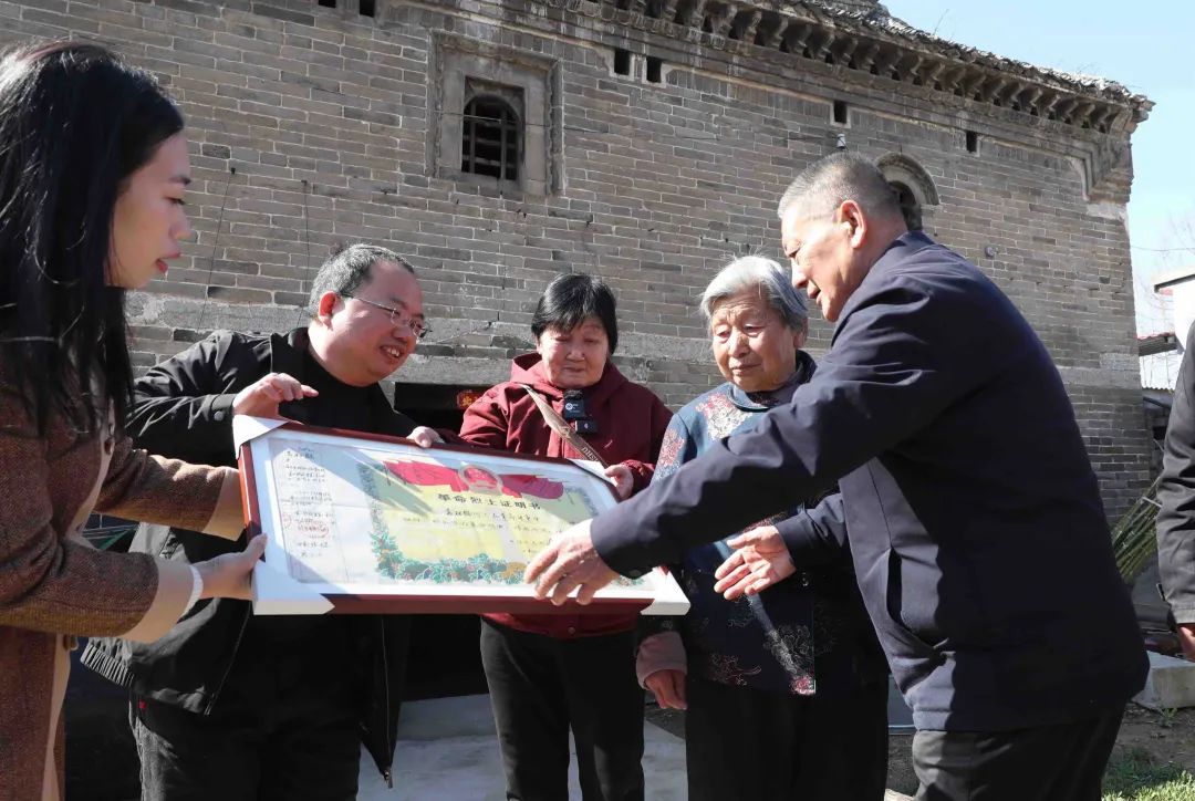 河南省許昌市建安區(qū)袁莊，曹明（左二）將修復(fù)好的革命烈士證明書交到袁松鶴烈士的家屬手中。