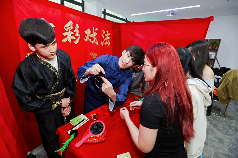 留學(xué)生學(xué)習(xí)古彩戲法的玩法。校方供圖
