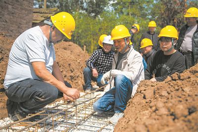 在湖南省常德市安鄉(xiāng)縣一建筑工地，技師（左一）向工人們講解扎筋技巧。新華社記者 周勉攝