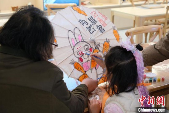 2月7日，浙江杭州，小朋友在綢布傘上體驗彩繪。春節(jié)期間，浙江省非物質(zhì)文化遺產(chǎn)館成為家庭出游的熱門之選，民眾在傳統(tǒng)技藝體驗中感受年味。中新社記者 曹丹 攝