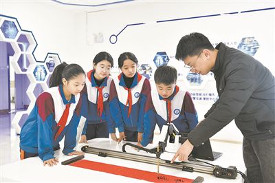 在山東日照金海岸小學(xué)，老師指導(dǎo)學(xué)生練習(xí)機(jī)械臂毛筆書寫編程。新華社記者 郭緒雷攝
