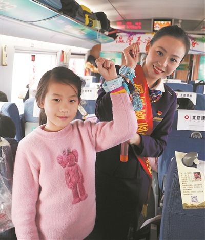 列車工作人員和小乘客展示防走失兒童專用手環(huán)。
