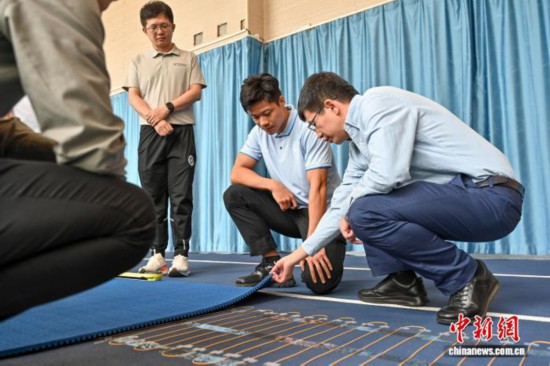 圖為蘇炳添在訓(xùn)練基地內(nèi)了解數(shù)字化跑道分析系統(tǒng)。中新社記者 陳驥旻 攝