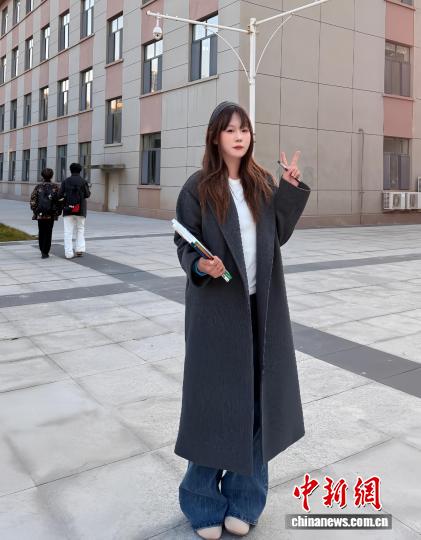 劉沫含在宿舍前拍照，她身著“雙十一”花200多元買的風(fēng)衣。 受訪者供圖